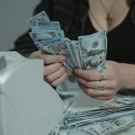 A woman counting cash with a money counter, symbolizing financial management.